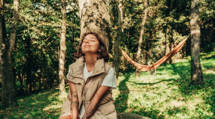 Una persona sentada debajo de un árbol disfrutando de la naturaleza en su escapada relax por España.