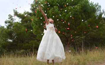 En la imagen se muestra una niña vestida con su vestido de primera comunión divirtiendose.